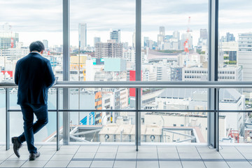 Asia Business concept for real estate and corporate construction - Asia businessman stand on window in high office with city skyline in Tokyo, Japan