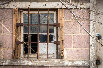 Rusty iron bars and wooden boards cover the window of an abandoned building.