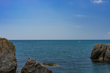 Seascape with a rocky shore line under a blue sky.
