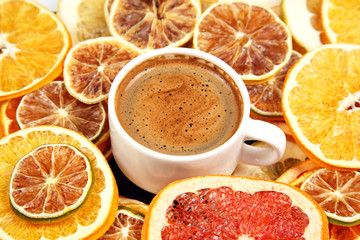Dried slices of various citrus fruits and black coffee in a white Cup