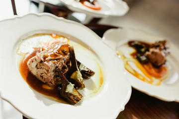 Many dishes loin of pork confit with artichokes and juicy sauce served by waiters in a luxury restaurant.
