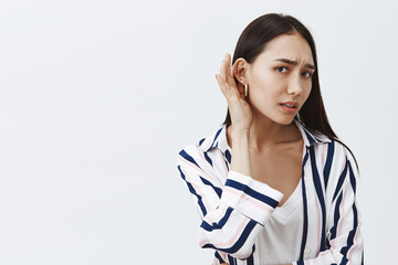 Studio shot of good-looking gloomy girlfriend with long dark hair, leaning towards camera with one...
