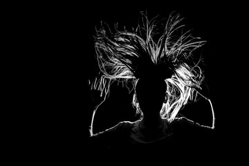 Fototapeta na wymiar art picture of a girl jumping in flight with her hair down to her sides in a contrasting light on an isolated black background