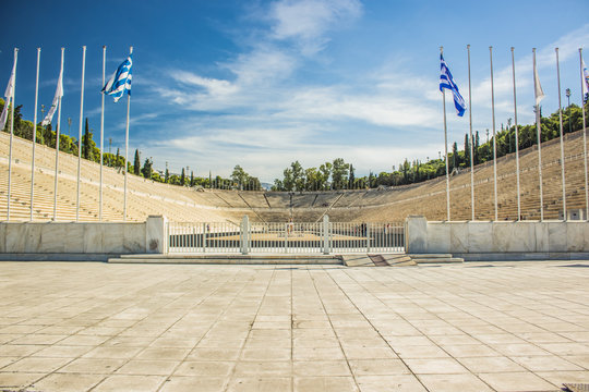 travel sightseeing touristic concept world heritage site of ancient stadium example of antique architecture, symmetry photography, Greek flags on pillars before enter 