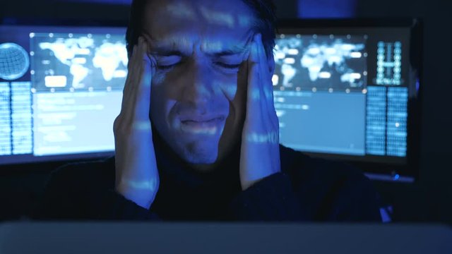 Portrait of Tired IT professional programmer in glasses is overworking on computer. He feeling headache