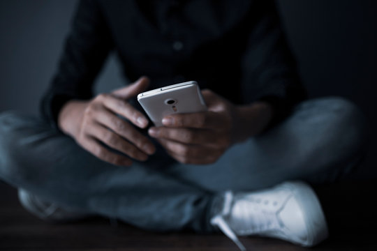 スマホを持って座り込む男性