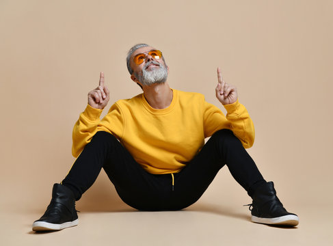 Portrait Of Gray Hair Senior Millionaire Man In Yellow Sunglasses Pointing Fingers Up