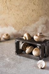 Raw champignons on a rustic wooden box