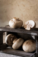 Raw champignons on a rustic wooden box