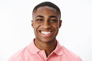 Headshot of happy successful and delighted young african american male student smiling broadly with...