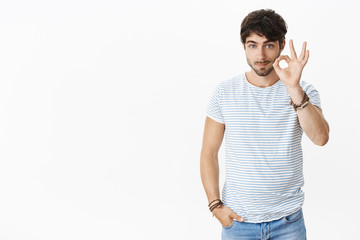 Fototapeta premium I got it, count on me. Portrait of chill and relaxed good-looking masculine male with beard and blue eyes feeling unbothered and carefree showing okay gesture assuring nothing worry about
