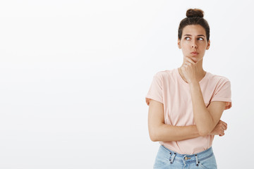 Hmm, nice plan. Portrait of thoughtful attractive and funny young european female with messy bun in...