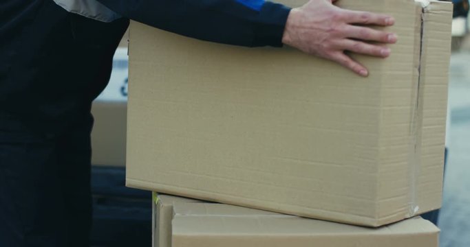Close up of the carton box parcel being taken out from the delivering white van. Outdoors.