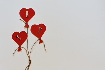 Stylized balloons in form of red hearts decorated with vintage figurines of lovers and symbolic keys on white background. Minimalism style.