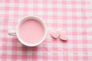 cup of milk and heart shape on pink tablecloth, Valentine's day background.