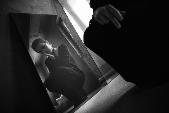 Girl with short hair sit near her reflection in the mirror