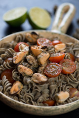 Fusilli made of hemp flour and served with tomatoes and mussels, close-up, selective focus