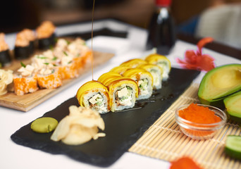 Freshly prepared sushi roll covered by teriyaki sauce and served with wasabi and marinated ginger. Special offer for lunch from three different sources with rice and seafood in Japanese restaurant.
