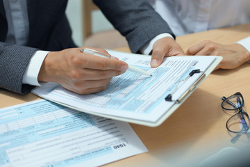 Man filling in U.S. Individual income tax return, tax 1040 at table.
