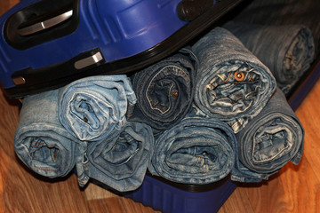 A stack of blue jeans in a blue suitcase
