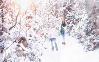 Young family for a walk. Mom and daughter are walking in a winter park.