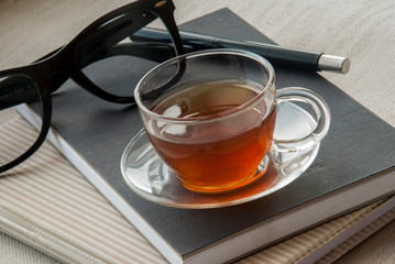 One glass pen, notebook, glasses and tea