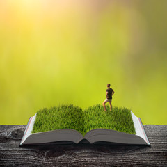 Young man in a green grass on the pages of book