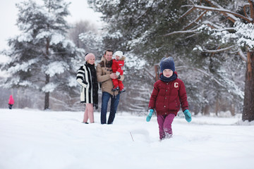 Young family with children are walking in the winter park. Winter walk of parents with children. Walking on a holiday weekend in the winter.