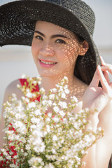 Close-up portrait of charming pretty asian woman with adorable smile wearing hat and holding flower posing. Asian model smile and look at camera.