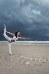 Young woman doing yoga exercise on the beach