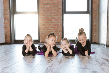 Obraz premium Cute little kids dancers on dance studio. Choreographed dance by a group of small ballerinas practicing at a modern ballet school