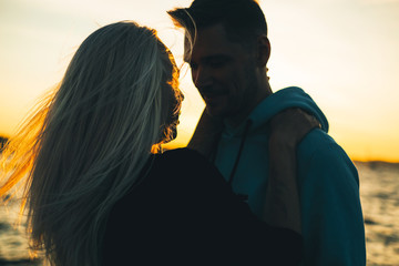 Silhouette of couple in love on the pier, sunset time, water bac