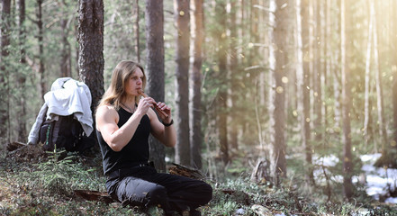 A musician with a tool in nature. A man is playing a flute in a pine forest. The music of the...