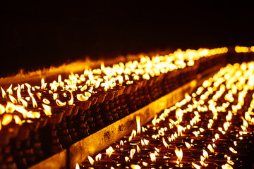 Many candle flames glowing in the dark