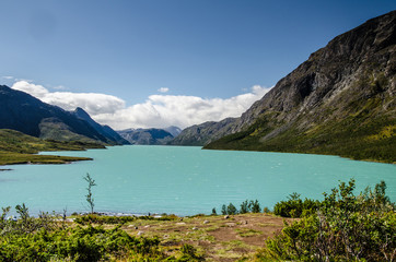 Amazing view of the crystal blue lake Gjende in Jotunheimen National Park with beautiful mountains behind and blue sky