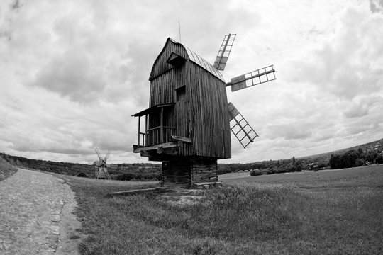 Black and white picture of the old wooden mills in the field near the village