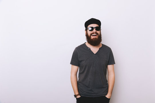 Photo of bearded man in hat and sunglasses with hands in pockets