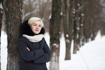 Young beautiful girl on a walk in winter park