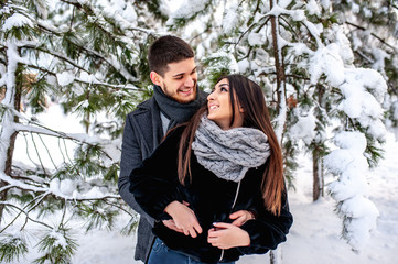 A loving young couple is resting in the mountains in a snow-covered forest. concept of joint rest