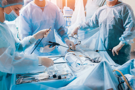 Process of gynecological surgery operation using laparoscopic equipment. Group of surgeons in operating room with surgery equipment