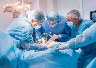 Process of trauma surgery operation. Group of surgeons in operating room with surgery equipment.