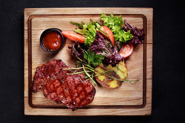ribeye steak served with vegetable salad and potatoes on board, traditional american cuisine,grill and barbeque, meat restaurant menu