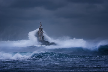 Big wave against old Lighthouse in the port of Ahtopol, Black Sea, Bulgaria on a moody stormy day....
