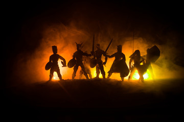 Fototapeta na wymiar Medieval battle scene. Silhouettes of figures as separate objects, fight between warriors on dark toned foggy background. Night scene.