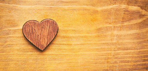 A little wooden heart on the wooden desk. And a big space for your text. Valentines concept