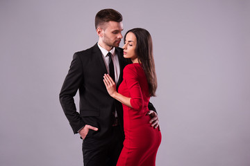 Love you so much! Beautiful stylish and elegant couple in suit and dress are hugging, have a fun and posing isolated in studio. Holidays and events. St Valentine's day. Day of lovers