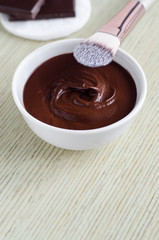 Small white bowl with diy cocoa (dark chocolate) face mask. Homemade beauty treatments.  Copy space.