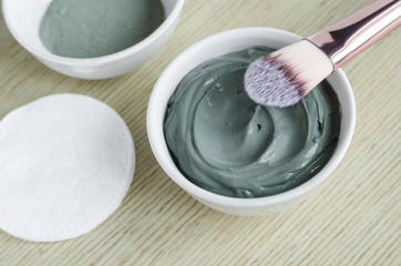 Small white bowl with blue cosmetic clay mask. Homemade beauty treatment. Copy space. 