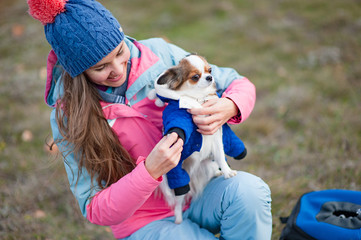 happy beautiful young woman dressing her little chihuahua dog in animal clothes