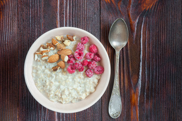 Delicious oatmeal with raspberry and nuts. Healthy diet. Top view. Copy space.